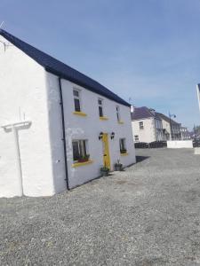 un edificio blanco con ventanas amarillas y una puerta amarilla en The Barn @Ardhill House en Ardara