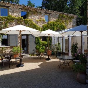 a patio with tables and umbrellas in front of a building at Le Mas Vigneron in Gordes
