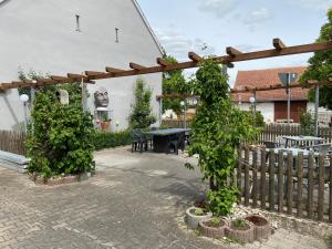a wooden pergola with two trees and a table at Landhotel Müller im Donautal in Tapfheim