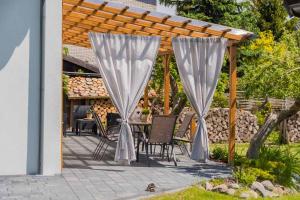 a patio with a table and chairs under a pergola at Hupkas Apartementy i Pokoje in Jantar