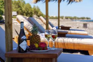 a table with two glasses of wine and a plate of fruit at Beach Houses Santorini in Kamari