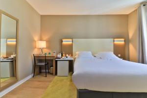 a hotel room with a large bed and a desk at Hotel Amiraute in Cannes