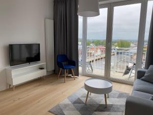 a living room with a tv and a blue chair at Apartamenty w Marina Royale in Darlowko