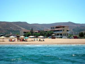 a beach with umbrellas and people on the beach at Gramvoussa Bay in Kissamos