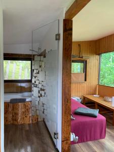 ein Schlafzimmer mit einem rosa Bett und einer Glaswand in der Unterkunft Trees House Parang in Petroşani