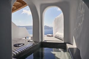 a pool in a house with a view of the ocean at Alisaris Cave Suites in Oia