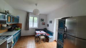 a kitchen with blue cabinets and a table and a refrigerator at Áron Apartman in Badacsonytomaj