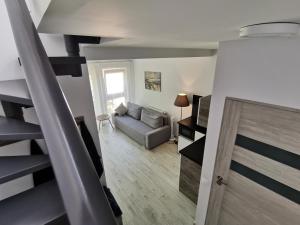 a living room with a couch and a stair case at Apartamenty Portowy in Mrzeżyno