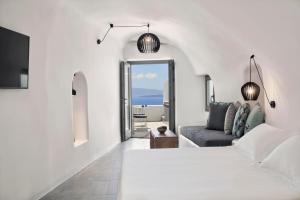 a white room with a bed and a couch at Alisaris Cave Suites in Oia