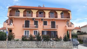 a pink house with balconies and a stone wall at Pansion Maria in Zadar