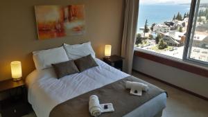 1 dormitorio con 1 cama grande y 2 toallas. en El encanto del lago en San Carlos de Bariloche