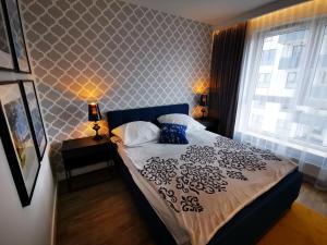een slaapkamer met een bed met een zwart-wit dekbed bij Walowa Tower Apartments in Gdańsk