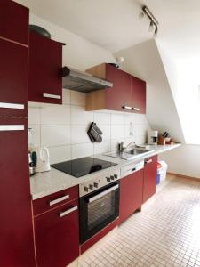 a kitchen with red cabinets and a sink at Dat Landhus in Büsumer Deichhausen