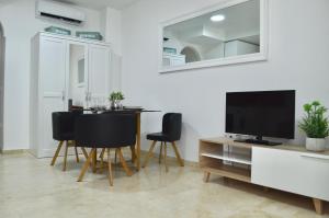 a living room with a table and a tv and chairs at Apartamento Adriana. Céntrico, a 50m de la playa. in Fuengirola
