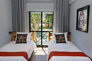2 Betten in einem Zimmer mit Fenster in der Unterkunft HI Setubal - Pousada de Juventude - CASA DO LARGO in Setúbal