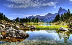 a lake in the mountains with a house in the water at Penelope Home by Casa e Lode in Passo del Tonale
