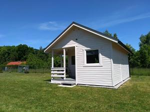 um pequeno galpão branco num campo de relva em Domki na górce em Kolczewo