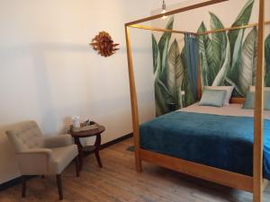 a bedroom with a canopy bed and a chair at la maison de Valbois in Varvinay