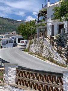 a road in front of a building with a bus at Hostal Atalaya en Capileira CB in Capileira