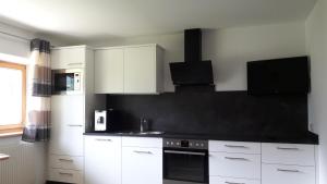 バルトロメベルクにあるFerienwohnung Rudigierの白いキャビネットと黒い壁のキッチン