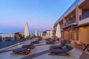 eine Reihe von Liegestühlen und Sonnenschirmen auf dem Balkon in der Unterkunft Lilium Luxury Suites in Agia Marina
