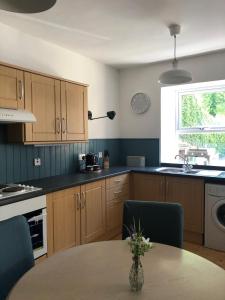 een keuken met houten kasten en een tafel en een raam bij Fox Cottage in Moffat