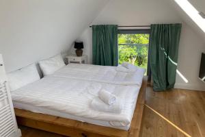 a bedroom with a large white bed with green curtains at Cottage@Baltic-Chalets in Kalkhorst