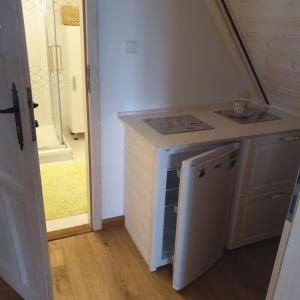 uma pequena cozinha com um lavatório e uma máquina de lavar louça em Malowniczy Zakątek w Dercu em Derc