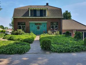 a house with a blue door and some bushes at De Vliegende Vlinder in Nederweert