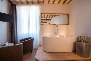 a bathroom with a large tub and a mirror at Dimora delle Muse in Montalcino