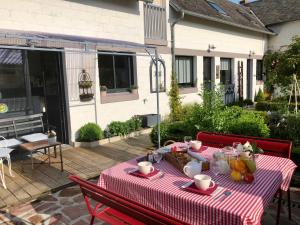 una mesa con un mantel rojo y blanco en un patio en Le grenier du jardin en Pontorson