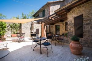 een patio met tafels en stoelen en een gebouw bij Dimora delle Muse in Montalcino