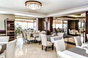 a restaurant with white chairs and tables and a chandelier at Simbad Hotel & Bar Superior in Mosonmagyaróvár