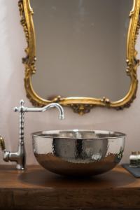 a bathroom sink with a copper bowl and a mirror at Dimora delle Muse in Montalcino