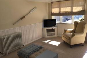 ein Wohnzimmer mit einem Stuhl und einem TV in der Unterkunft Mudeford Mews in Mudeford