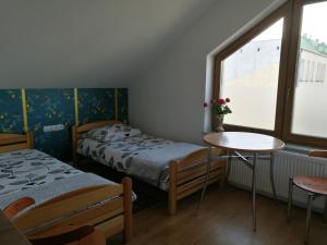 a room with two beds and a table and a window at Suwałki Centrum Apartament in Suwałki