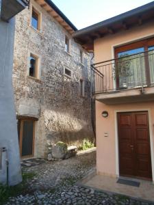ein Steingebäude mit einer braunen Tür und einem Balkon in der Unterkunft La grotta dell'Antica Calvasino - Jacuzzi in Lezzeno