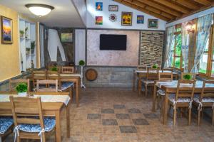 a restaurant with wooden tables and chairs and a flat screen tv at Chrystal Guest House in Obzor