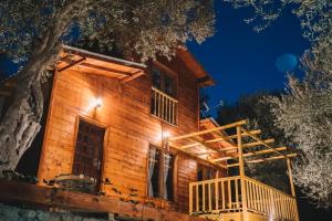 eine Blockhütte mit einer Terrasse in der Nacht in der Unterkunft Cottage Four Olives in Ulcinj