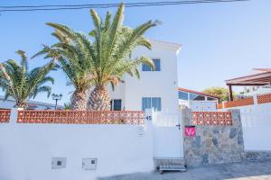 a white house with palm trees behind a fence at Aguamarina in Tarajalejo