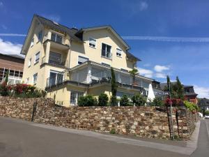 ein großes Haus an einer Steinmauer mit einem Zaun in der Unterkunft Ferienwohnung „Die 3 am Rhein“ in Rüdesheim am Rhein