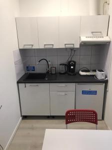 uma pequena cozinha com armários brancos e uma cadeira vermelha em Chopin apartments self check-in em Varsóvia