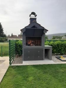a outdoor fireplace in a yard with grass at Holiday House Petra - Imotski - Makarska in Imotski
