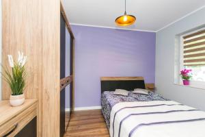 een slaapkamer met paarse muren en een bed bij Apartament nad morzem. Gdańsk Wyspa Sobieszewska in Gdańsk