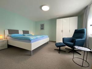 a bedroom with a bed and a blue chair at Apartment am Kaffelstein - mit Terrasse in Kreuzwertheim