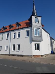 duży biały budynek z wieżą na ulicy w obiekcie Ferienwohnung Leilas Lodge w mieście Langelsheim