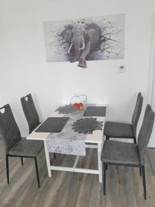 een eettafel met stoelen en een olifantenfoto aan de muur bij Ferienwohnung Leilas Lodge in Langelsheim
