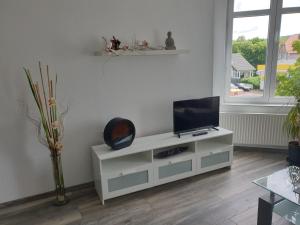a living room with a tv on a white cabinet at Ferienwohnung Leilas Lodge in Langelsheim
