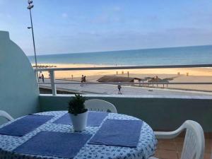 una mesa en un balcón con vistas a la playa en GATU PREMIUM Villa Isabel TERRAZA,PARKING,1ºLINEA PLAYA,WIFI,VISTA AL MAR en Cádiz