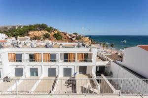 ein weißes Gebäude mit dem Ozean im Hintergrund in der Unterkunft Apartamento sobre a praia in Olhos de Água
